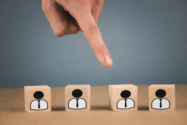 Choice of an employee leader from the crowd. the hand points to the wooden cube that symbolizes that the hand makes the choice.